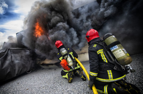 Un binôme de sapeurs-pompiers à l'attaque d'un feu au moyen d'une lance à eau